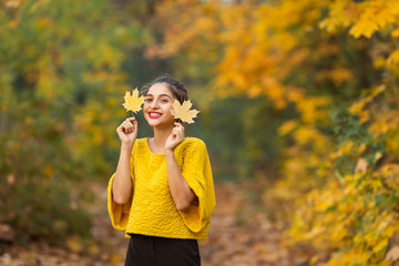 Cheerful woman portrait with autumn maple leaves in the park
