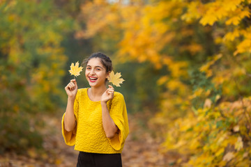Fototapeta premium Cheerful woman portrait with autumn maple leaves in the park
