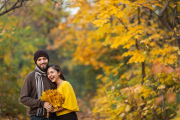 Happy couple in the autumn park. Young family having fun outdoors