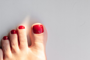 Close up photo of a beautiful female feet with red pedicure on white background. Red nail polish