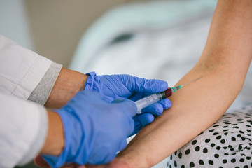 A shallow focus shot of a nurse drawing blood from the arm of a female patient