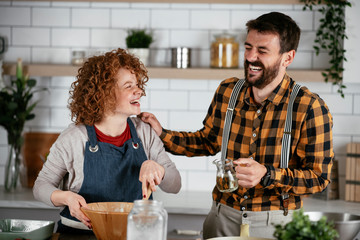 Boyfriend and girlfriend making delicious food at home. Loving couple cooking in kitchen..