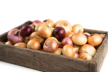 Yellow and red onions in a rustic wooden box isolated on a white background, side view. Full frame. Vegetable background. Concept of food, farm products.