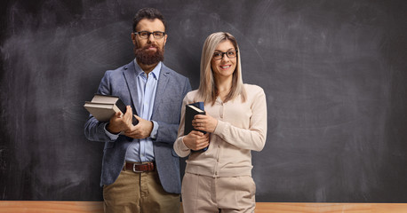Male and female teacher standing in front of a school blackboard