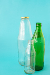 Empty glass transparent and green bottles on a blue background. A copy of the space. Ecology and Zero waste concept