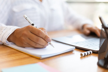 Cropped image of female manager taking notes with pen