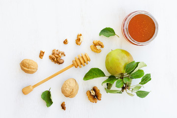 Honey, apples and walnuts on white wooden background