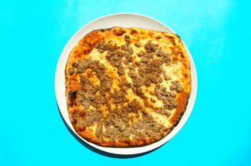 Famous traditional Arabic, Middle East, Israel cuisine. Mutton minced meat Manakeesh on dark wooden background. Lahmeh Bajein Manakish on white plate. Top view