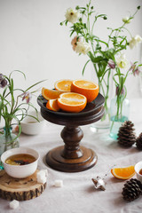 Oranges on a wooden stand. Spring still life with fruits and flowers.