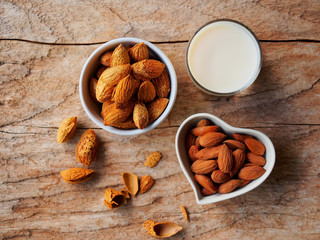 Raw almonds nut and almond milk top view on a rustic wooden table for healthy eating or vegetarian food concept.