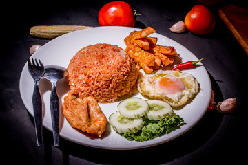 Fried rice with tomato sauce, garnished with sausage, fried chicken and egg