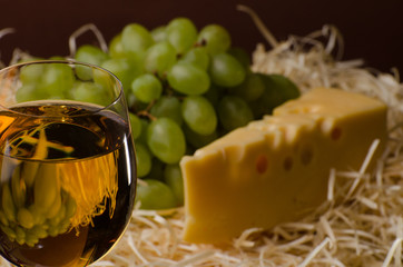 A glass of white wine with cheese and grapes. Still life