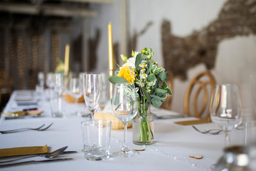 The composition of flowers and greenery standing on served table in the area of wedding party. Rustic wedding place. 