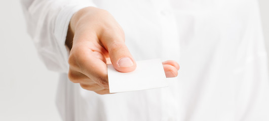  girl in a white office shirt holds out a business card. close portrait.
