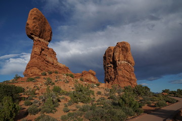 Fototapeta na wymiar Balanced Rock in Arches National Park with dark stormy clouds rolling in, daytime. Famous landmark inside Arches National Park in Moab, Utah, USA.