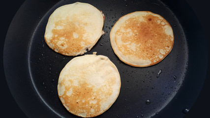 Delicious thin pancakes on a non-stick pan. Top view. Flat lay. Cooking process. Pancakes recipe.	