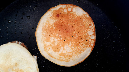 Delicious thin pancakes on a non-stick pan. Top view. Flat lay.  Cooking process. Pancakes recipe.