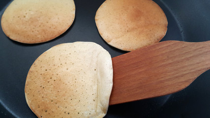 Delicious thin pancakes on a non-stick pan. Top view. Flat lay. Cooking process. Pancakes recipe.	
