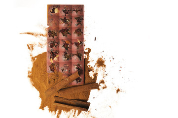 Bar of pink chocolate with raisins and fruits on a background of cinnamon sticks close up