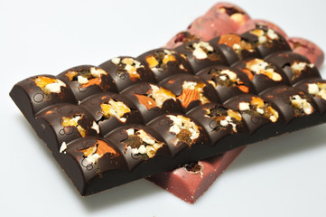 Two bars of milk and pink chocolate with raisins and dried apricots close-up
