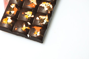 Bar of milk chocolate with raisins and dried apricots on a background of cinnamon sticks close-up