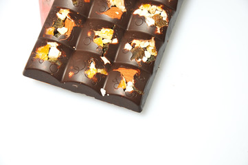 Bar of milk chocolate with raisins and dried apricots on a background of cinnamon sticks close-up