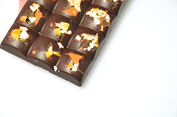 Bar of milk chocolate with raisins and dried apricots on a background of cinnamon sticks close-up
