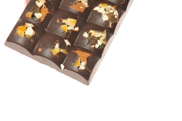 Bar of milk chocolate with raisins and dried apricots on a background of cinnamon sticks close-up