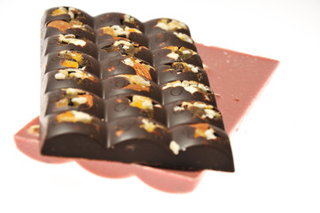 Two bars of milk and pink chocolate with raisins and dried apricots close-up