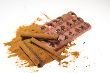 Bar of pink chocolate with raisins and fruits on a background of cinnamon sticks
