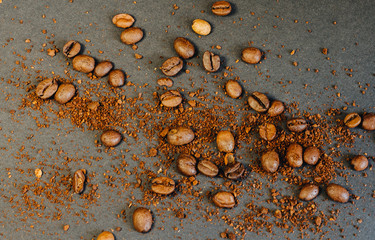 Coffee beans and ground coffee beans scattered on a black background in a warm tone