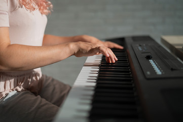 Close-up of female hands on the electric piano. Woman musician plays a keyboard instrument.
