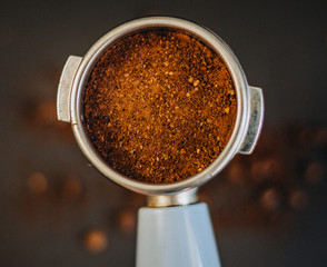 Coffee filter holder and roasted beans scattered on black background.