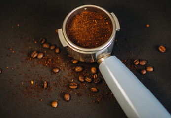 Coffee beans and ground coffee spilling out of a coffee filter holder