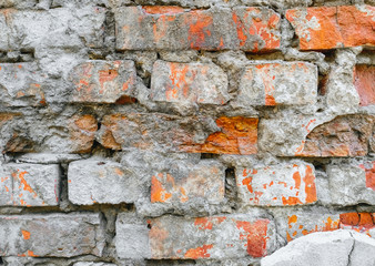 The texture of an old wall of red, orange uneven bricks with gray cement and concrete. Photography, abstraction, background.