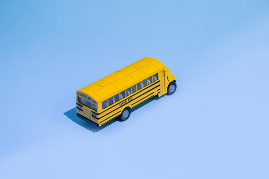 Back to school concept. Traditional yellow school bus on blue background. Transfer to school. Yellow toy model school bus.