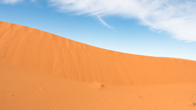 Panoramic image of a desert dune and the top of the photo with blue sky. Desert landscape