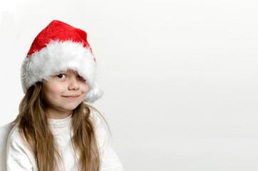Smiling child, girl in Santa Claus hat on light background with copy space