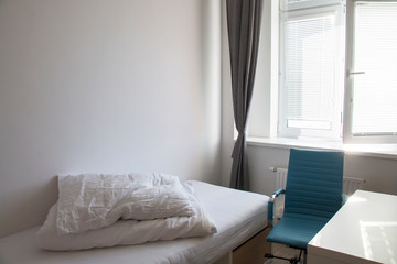 Comfortable bed with cushions in the room opposite the window table