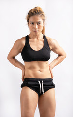 Portrait of sporty young asian woman with muscular body, posing against white background. Showing some strong abs and flat belly six pack.
