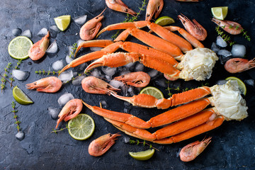 Fresh crab claws, lime, spices, spices, ice, shrimp, vegetables on a dark background. Delicious seafood, healthy food