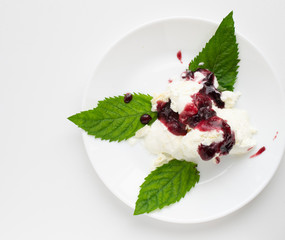 ice cream on a white plate with mint leaves poured with sorodin jam