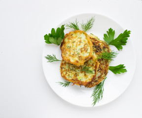 zucchini pancakes on a white plate with parsley leaves.