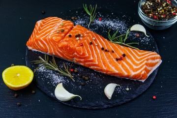 Raw salmon fillet with spices on black slate