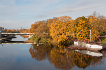 autumn yellow trees over the river and ship in the city of Jelgava, Latvia