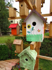 Many birdhouses are hung on a wooden structure that imitates a tree. Some of them are painted. Vertical photo