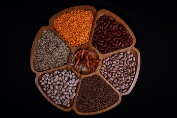 Red lentils, black lentils, red beans and white beans on wooden tray