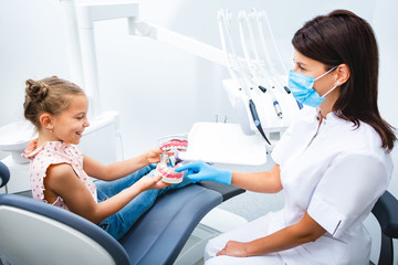 Fototapeta premium Little patient playing with dentist. Smiling little girl visiting dentist. Children's teeth treatment.