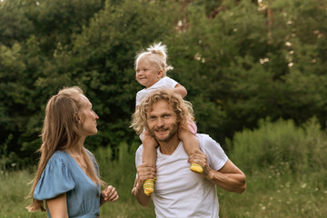 Happy family in the Park at sunset. Summer picnic. The concept of a healthy family. Mom, dad, daughter. Weekend in nature.