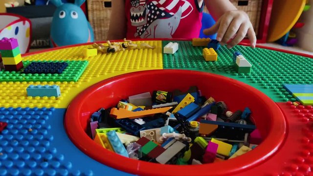 little boy playing with building blocks on his block table with men dolls 